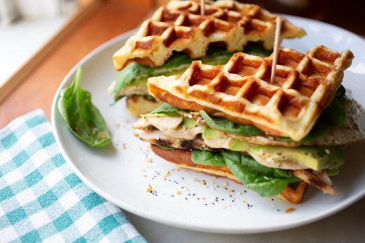 High-Protein Power Waffle Sandwich made with Heavenly Waffles, layered with grilled chicken, avocado, hummus, egg whites, and fresh greens.