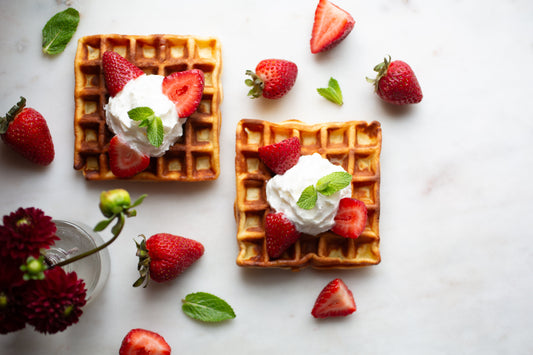 Stack of Heavenly Waffles topped with homemade whipped cream and fresh strawberries.