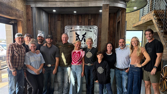 Chef Bob Haney of Heavenly Waffles smiling alongside the McBee family at McBee Farms kitchen table, both families gathered together enjoying waffles and celebrating the partnership.