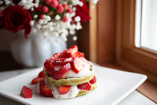 Stack of matcha protein waffles topped with fresh strawberries and vanilla Greek yogurt sweetened with monk fruit.