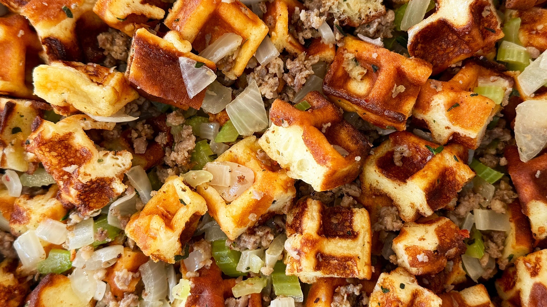 Golden holiday stuffing made with Heavenly Waffles cubes, garlic butter, sausage, herbs, onions, and celery in a warm casserole dish.
